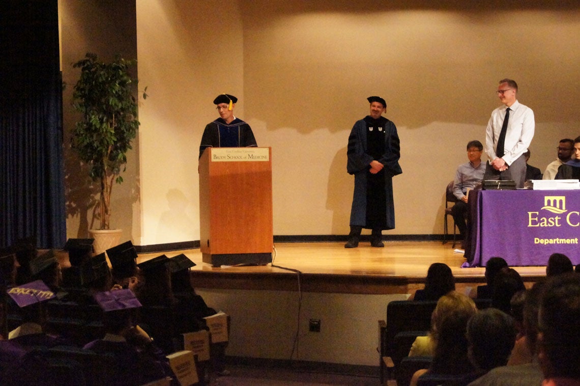 Faculty standing on stage at a graduation ceremony.