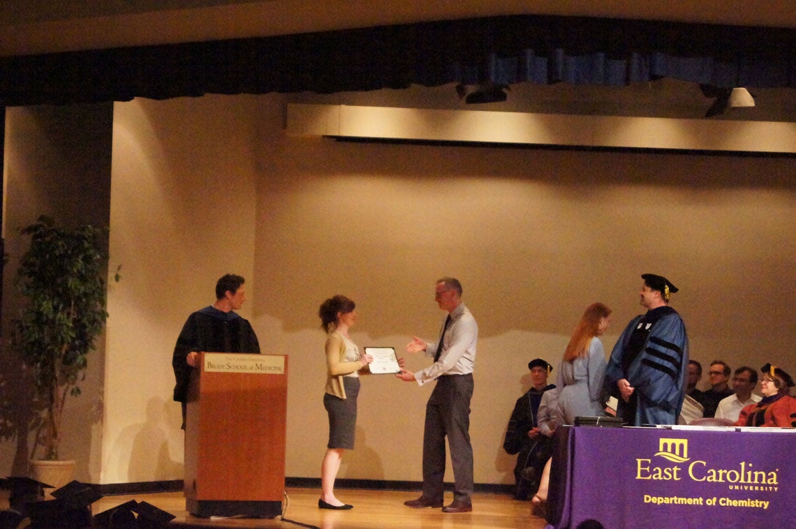 A student receives her degree on stage at a graduation ceremony.
