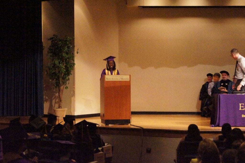 Undergraduate student speaks to the graduating class behind a podium on stage.