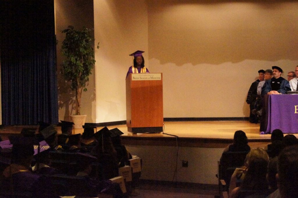 Undergraduate student speaks to the graduating class behind a podium on stage.