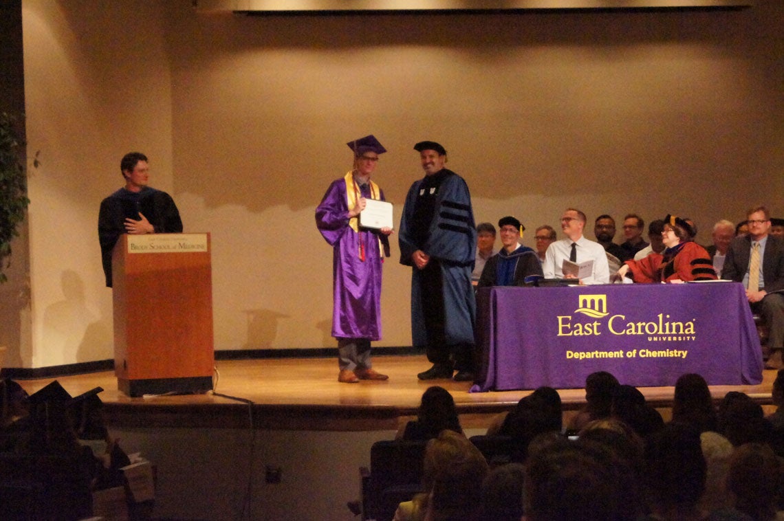 Undergraduate student receives her degree on stage at a graduation ceremony.