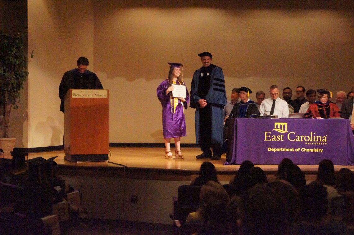 Undergraduate student receives her degree on stage at a graduation ceremony.