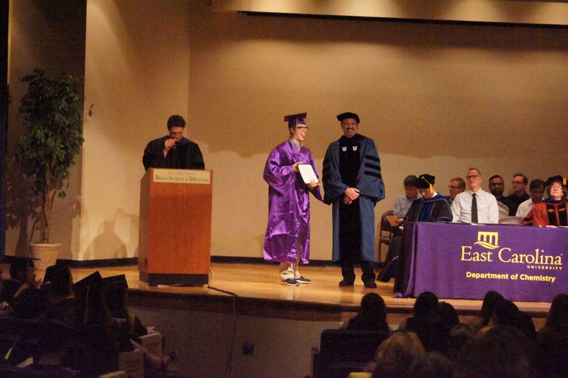 Undergraduate student receives his degree on stage at a graduation ceremony.