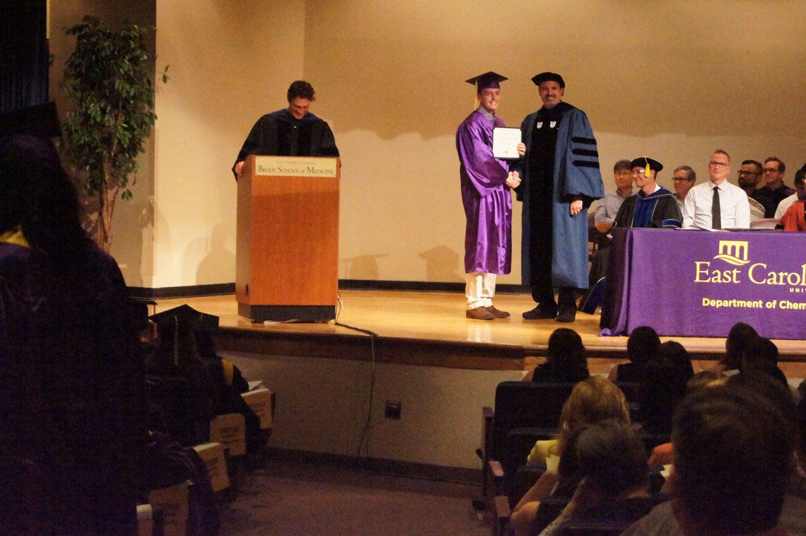 Undergraduate student receives his degree on stage at a graduation ceremony.
