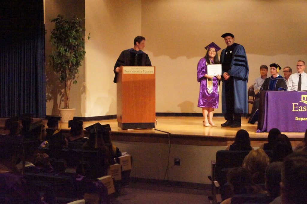 Undergraduate student receives her degree on stage at a graduation ceremony.