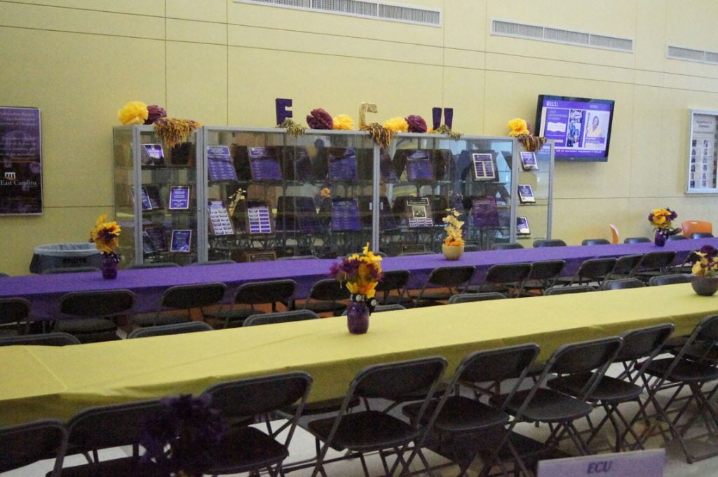 Long tables with purple and gold tablecloths and centerpieces.