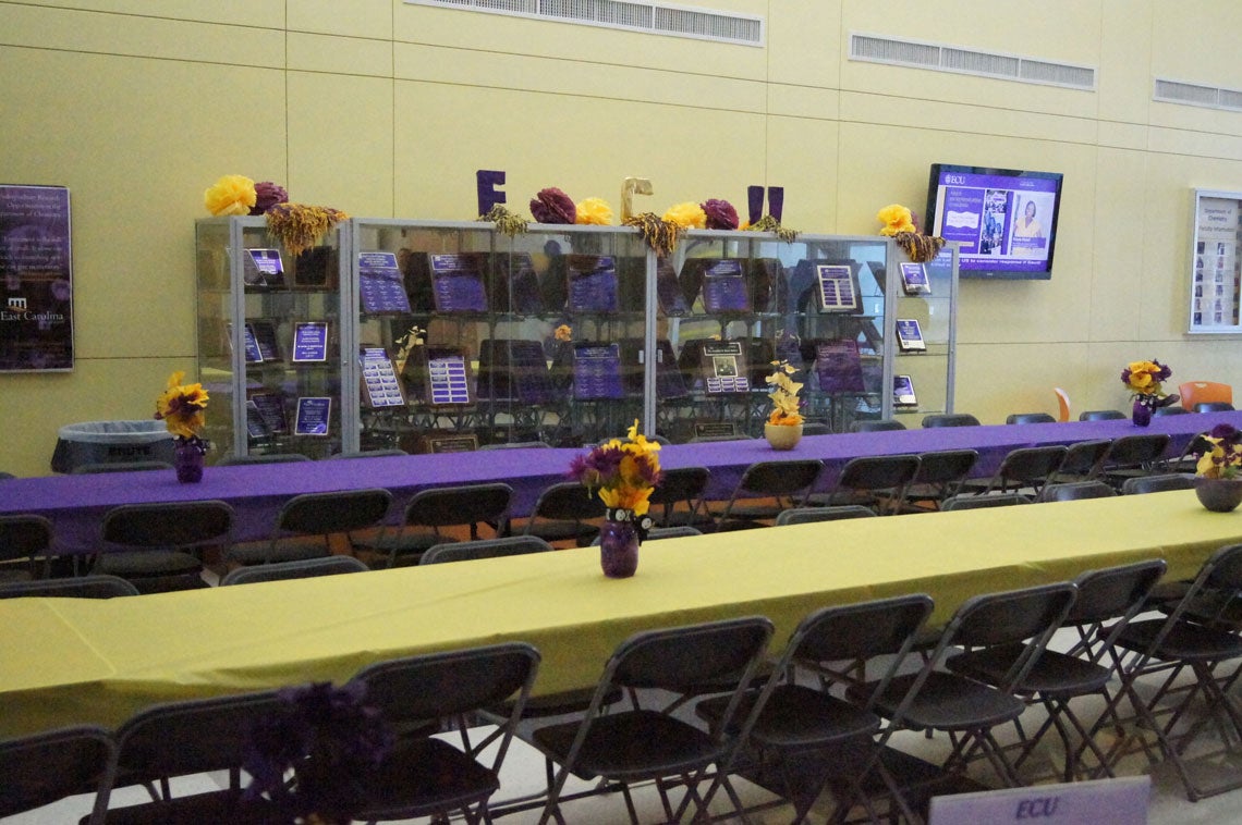 Long tables with purple and gold tablecloths and centerpieces.
