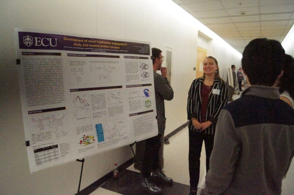 Students presenting their posters in a hallway.