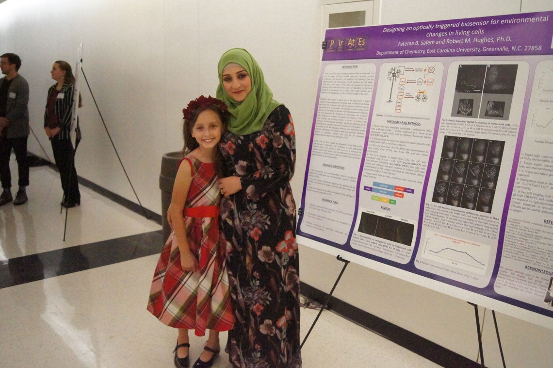 Fatema Salem with her daughter and her research poster.