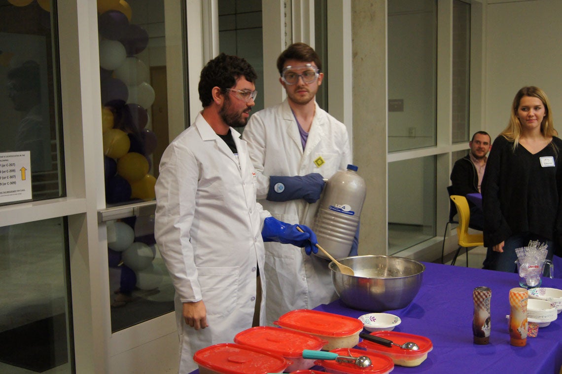 Two men in lab coats and goggles preparing to make ice cream with liquid nitrogen.