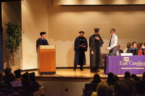 Graduate student on stage getting his hood.