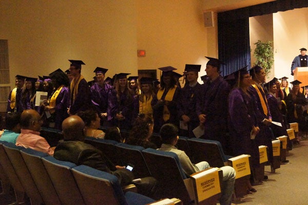 Group of graduates standing in an auditorium.